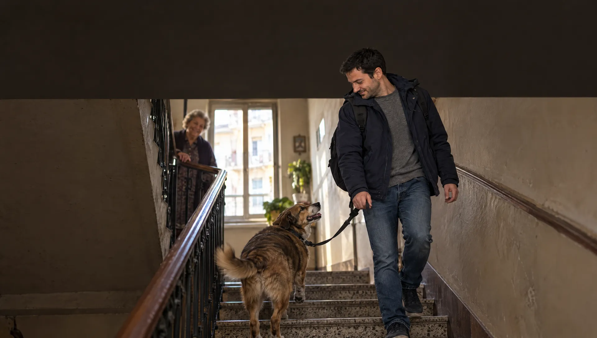 Sulle scale col cane al guinzaglio, la vicina lo saluta